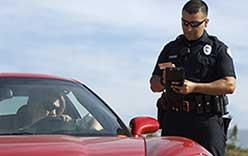 Police officer writing ticket next to car